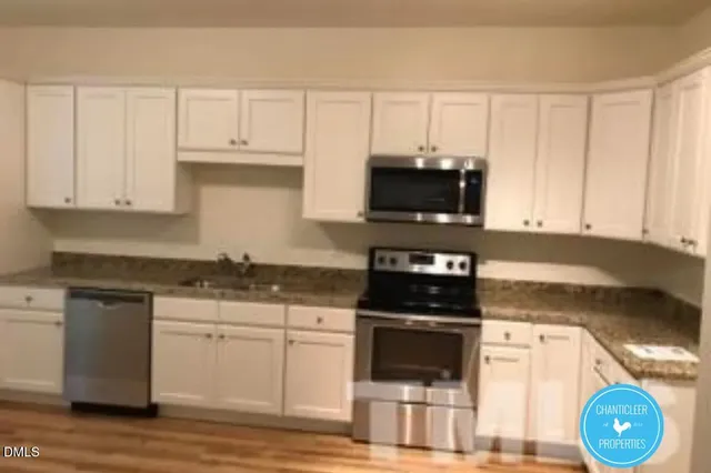 a kitchen with granite countertop a stove a microwave a sink and cabinets