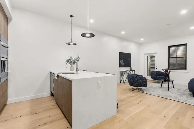 a living room with furniture a flat screen tv and kitchen view