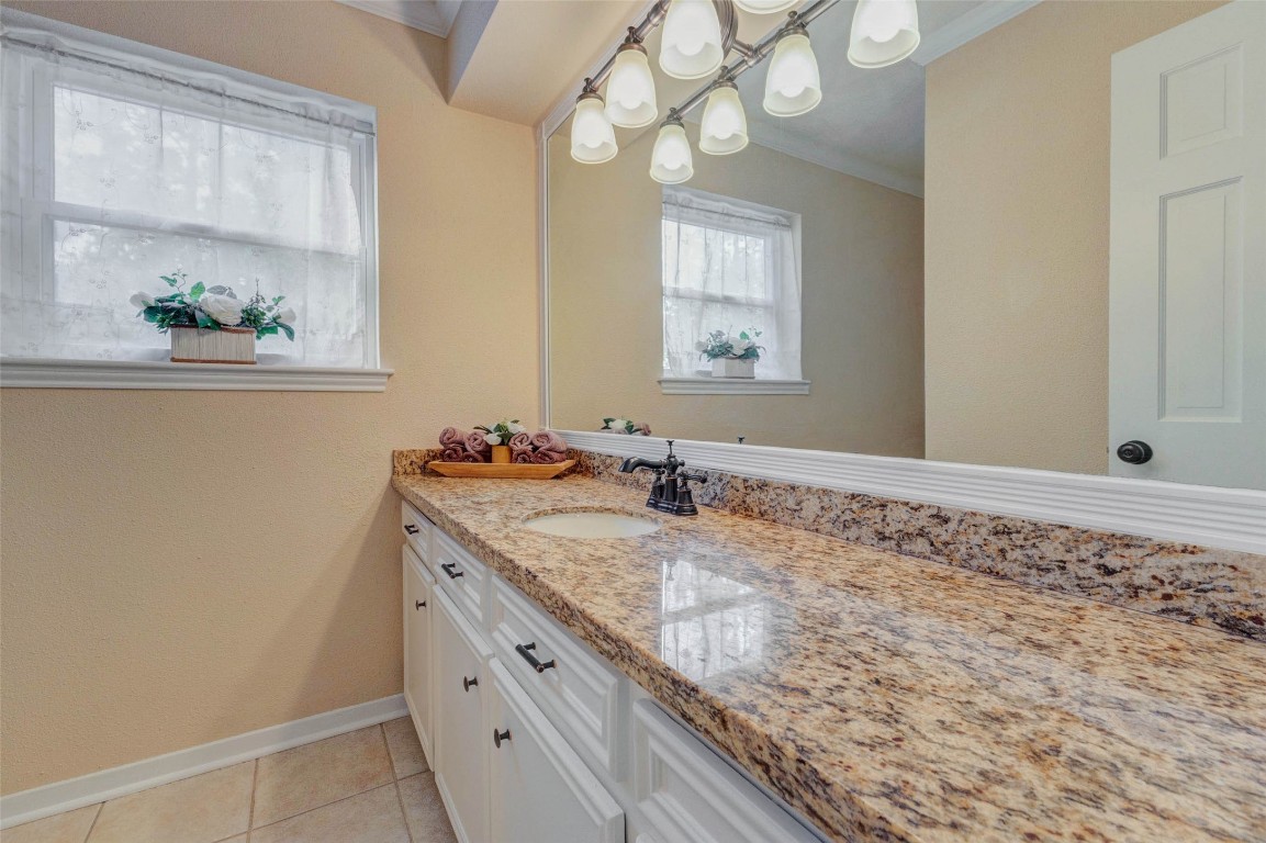 6710 Falling Waters Drive Spring, TX 77379 - Photo 17 of 45 This bathroom features a granite countertop with an under-mount sink, elegant under-cabinet lighting, and ample storage space. The large mirror and soft neutral tones create a bright and inviting atmosphere.
