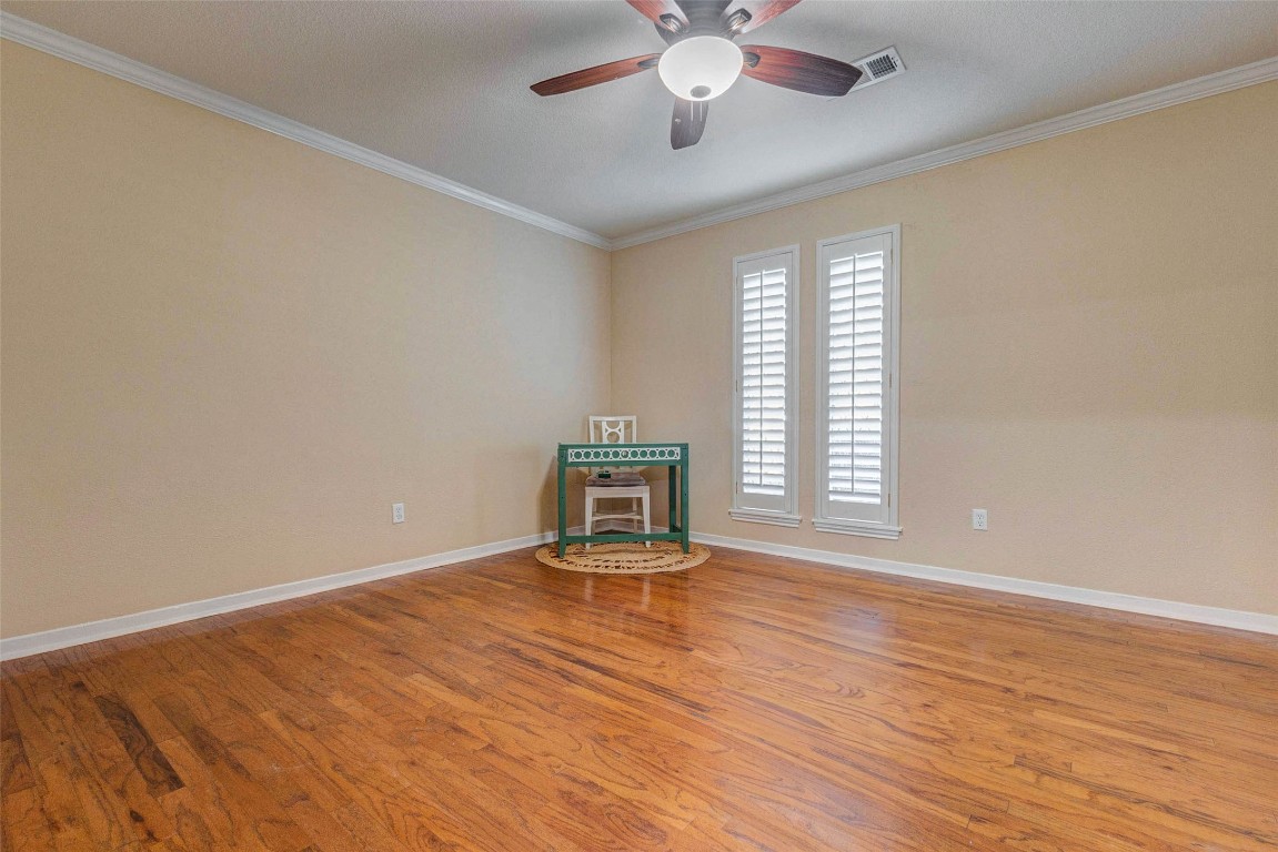 6710 Falling Waters Drive Spring, TX 77379 - Photo 25 of 45 The flex room features warm hardwood flooring, neutral walls, and a ceiling fan. It is well-lit with natural light from two tall windows with shutters, creating a cozy and inviting atmosphere.