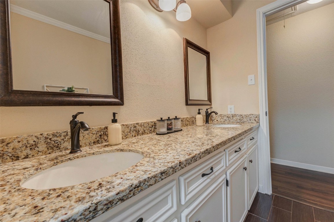 6710 Falling Waters Drive Spring, TX 77379 - Photo 33 of 45 This bathroom features a double vanity with granite countertops, elegant dark faucets, and framed mirrors. The cabinetry is painted white, complementing the warm, neutral wall color, while overhead lighting adds a bright touch.