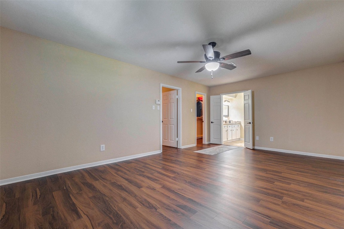 6710 Falling Waters Drive Spring, TX 77379 - Photo 34 of 45 The spacious primary bedroom features warm wood flooring, neutral walls, and a ceiling fan. It has direct access to a walk-in closet and a bright bathroom with double sinks, ideal for comfort and convenience.