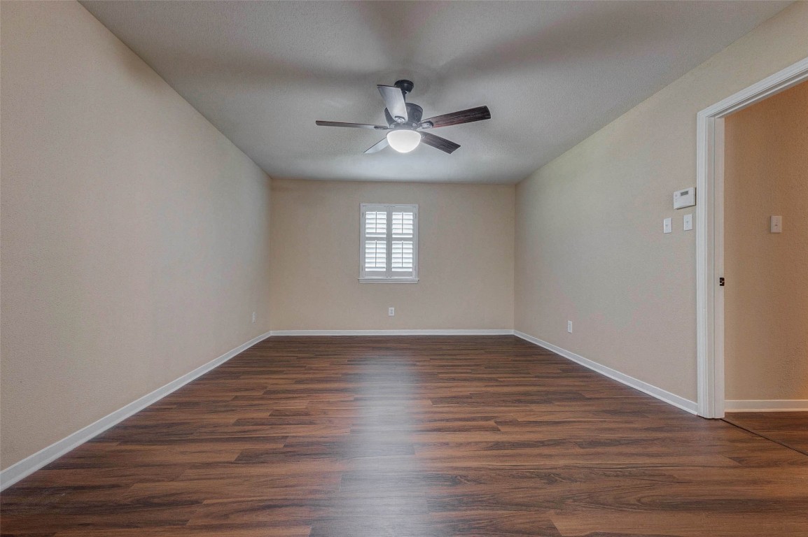 6710 Falling Waters Drive Spring, TX 77379 - Photo 35 of 45 This room features engineered wood flooring, neutral walls, and a ceiling fan with light. It has a window with shutters and a doorway leading to another area, creating a clean, versatile space.