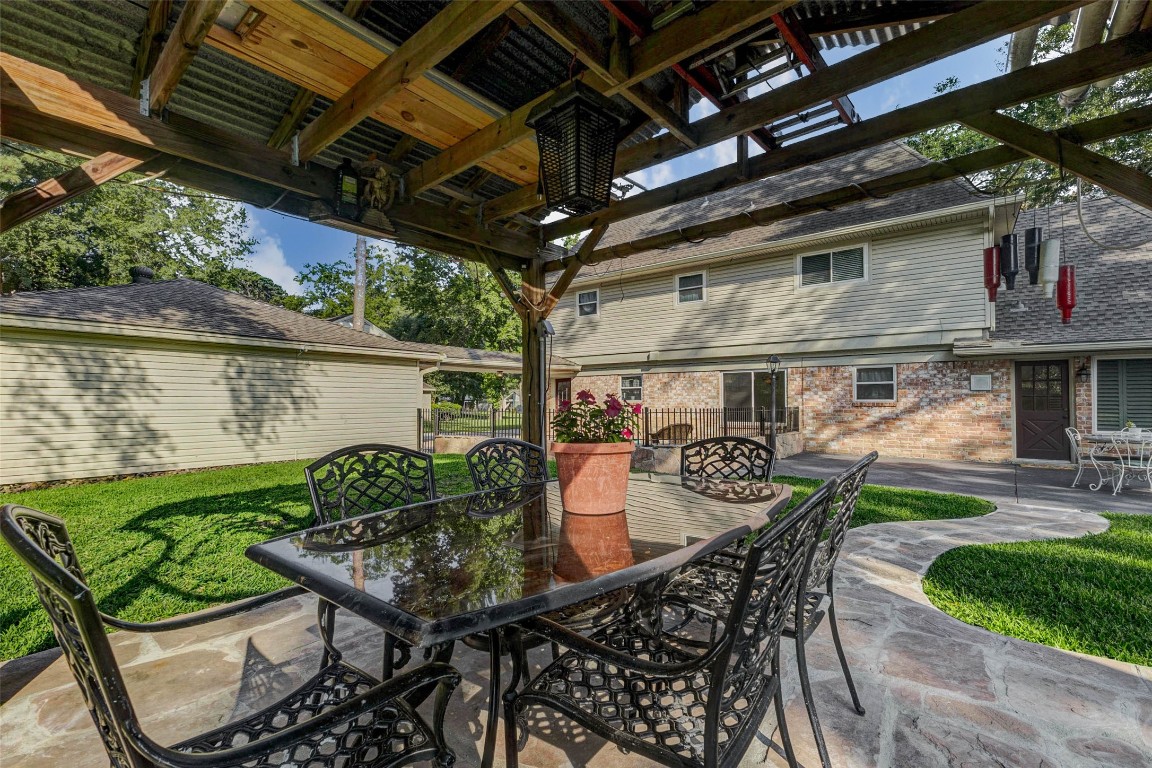 6710 Falling Waters Drive Spring, TX 77379 - Photo 43 of 45 This photo features a spacious backyard with a covered patio/gazebo, complete with a stylish outdoor dining set. The area is well-maintained, offering lush green grass and a paved walkway leading to the house, perfect for outdoor entertaining.