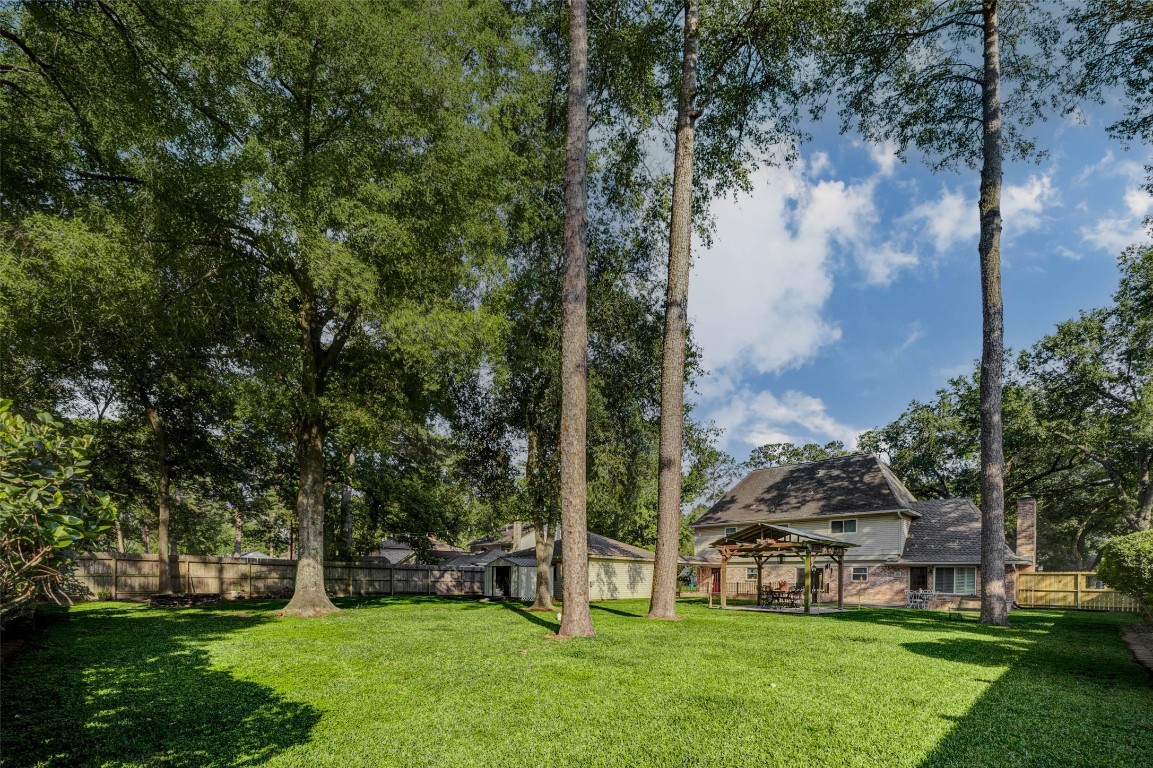 6710 Falling Waters Drive Spring, TX 77379 - Photo 44 of 45 Spacious backyard with lush green lawn, tall trees providing shade, and a well-maintained wooden fence. Plenty of space to build your own pool!