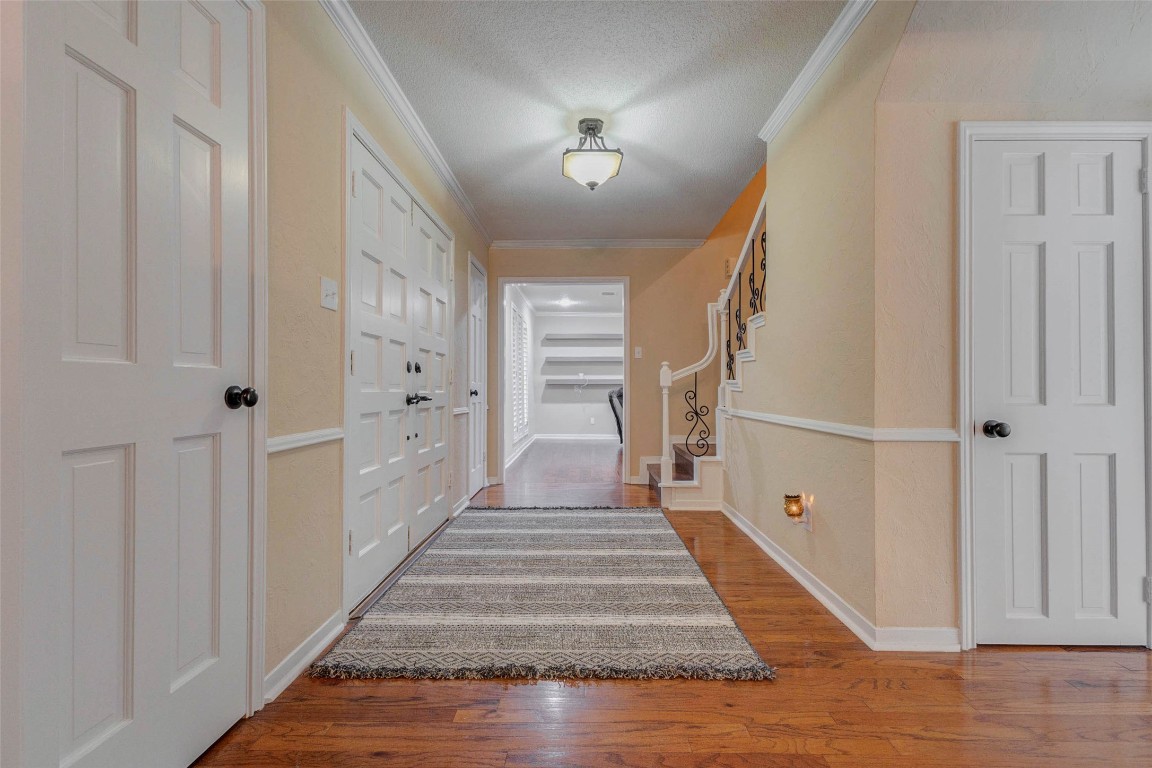 6710 Falling Waters Drive Spring, TX 77379 - Photo 6 of 45 This inviting hallway features warm wood flooring, soft beige walls, and a stylish central light fixture. It includes a large double-door entry and a staircase with elegant wrought-iron details.