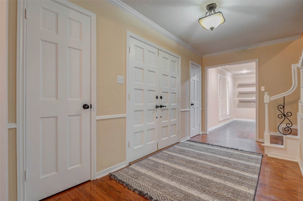 6710 Falling Waters Drive Spring, TX 77379 - Photo 7 of 45 This welcoming entryway features warm-toned walls and hardwood flooring. It includes a central light fixture, multiple doors, and a staircase with decorative iron balusters. A hallway leads to additional living spaces.