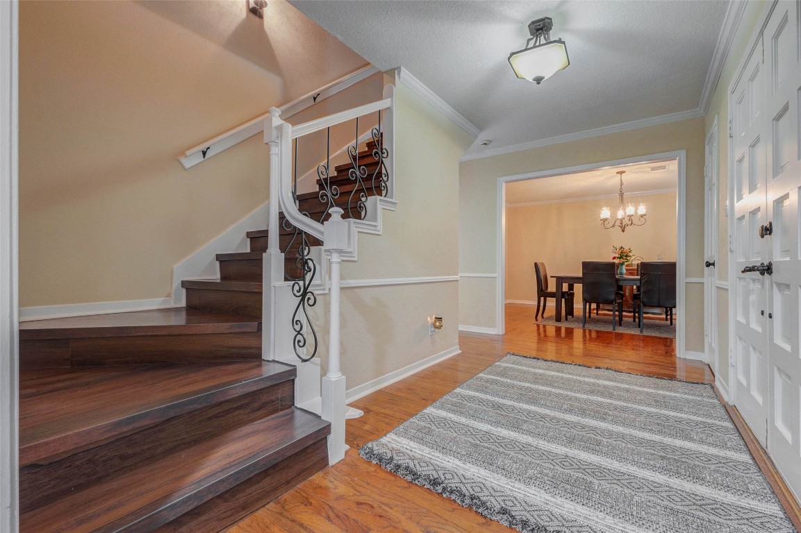 6710 Falling Waters Drive Spring, TX 77379 - Photo 8 of 45 The inviting home features a warm entryway with wood flooring, a stylish staircase, and an elegant iron railing. The hallway leads to a spacious dining area with a chandelier, perfect for entertaining.