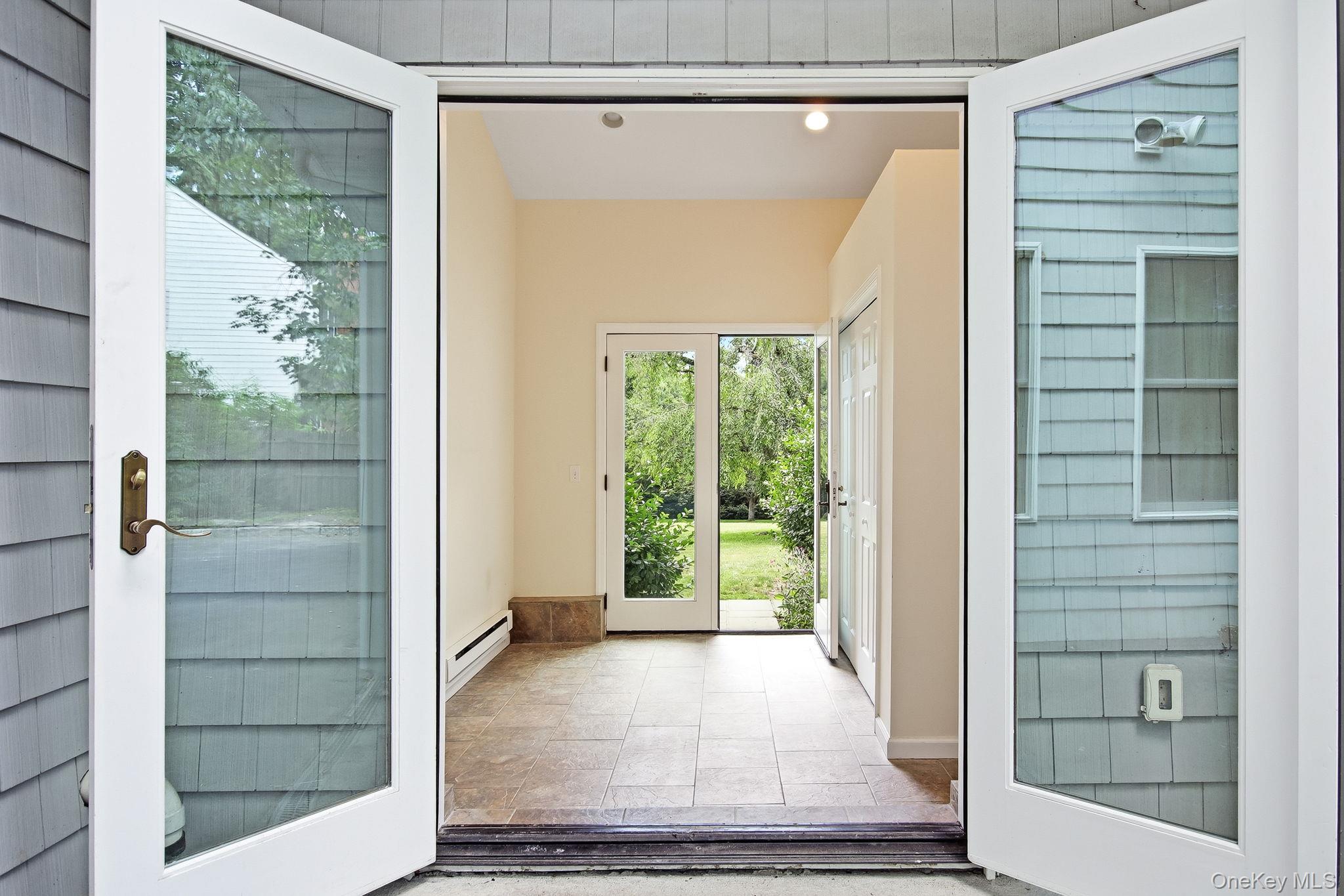 26 Century Ridge Road Purchase, NY 10577 - Photo 33 of 50 Breezway connecting the garage to the home and front yard to the back; exterior entry featuring white French doors opening into a tiled interior space
