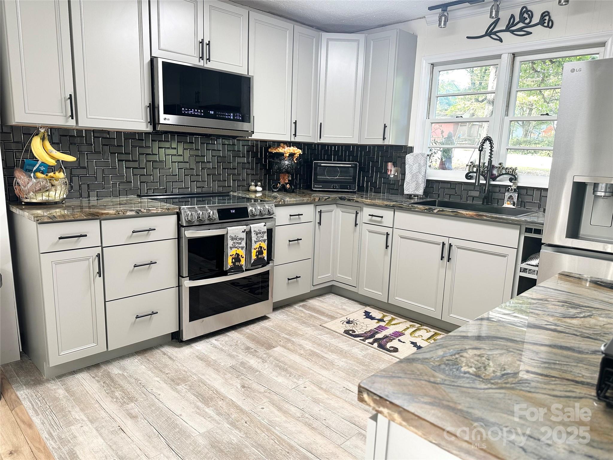 400 Charles Street Spencer, NC 28159 - Photo 7 of 26 a kitchen with stainless steel appliances granite countertop a stove a sink and a microwave