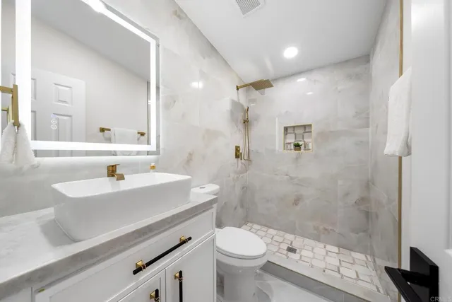 a bathroom with a sink a toilet a mirror and shower