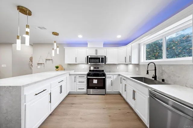 a kitchen with white cabinets stainless steel appliances and sink