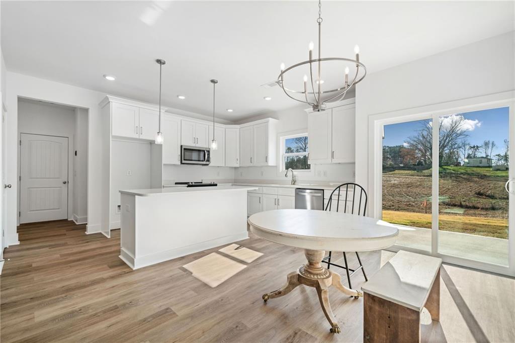 518 Old Canton Road Ball Ground, GA 30107 - Photo 9 of 42 a kitchen with stainless steel appliances granite countertop a table chairs stove and wooden floor