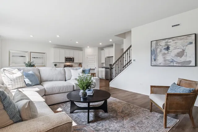 a living room with furniture potted plant and kitchen view