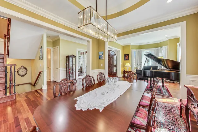 a kitchen with stainless steel appliances kitchen island granite countertop a refrigerator a stove a sink dishwasher a dining table and chairs with wooden floor