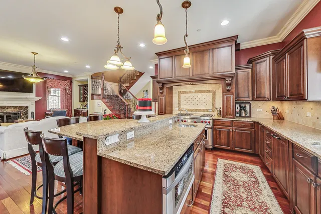 a kitchen with stainless steel appliances granite countertop a sink a stove top oven a chimney and a center island