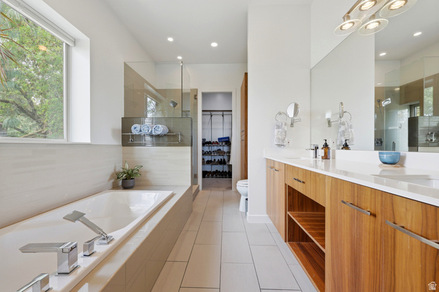 1389 Millbrook Way Bountiful, UT 84010 - Photo 35 of 74 Spacious bathroom featuring a built-in soaking tub with chrome fixtures, a walk-in shower with glass enclosure, a double vanity with wood-finish cabinetry, and white countertops