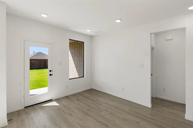 a view of an empty room with a window and wooden floor
