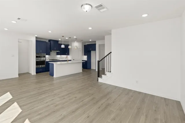 a view of kitchen with kitchen island wooden floor center island and stainless steel appliances