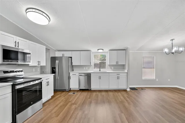 a kitchen with stainless steel appliances a stove top oven a sink dishwasher and a refrigerator with wooden floor