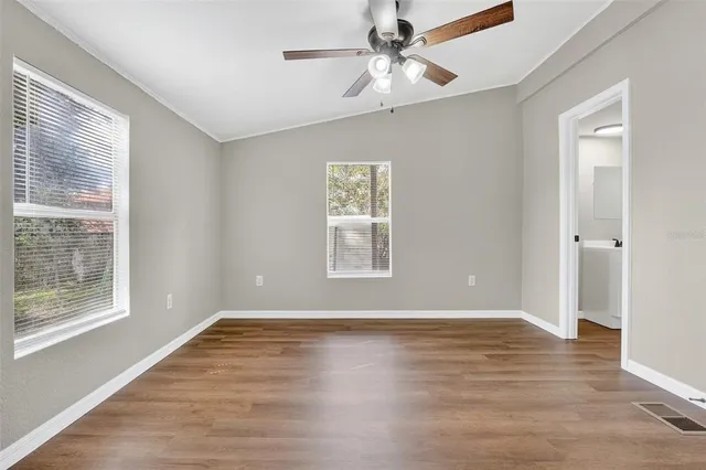 a view of an empty room with wooden floor and a window