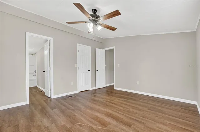 an empty room with wooden floor and ceiling fan