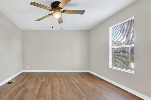 an empty room with a window and a fan
