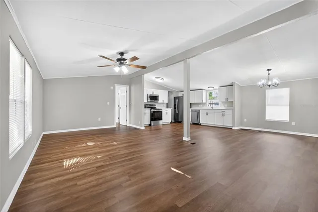 a view of an empty room with a kitchen and a window