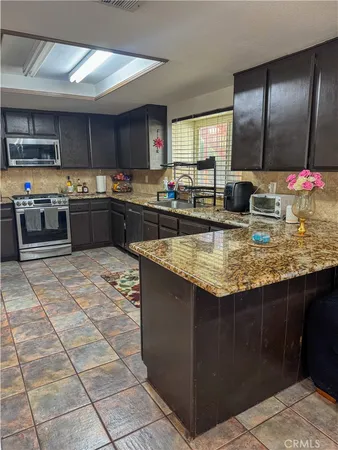 a kitchen with stainless steel appliances granite countertop a stove a sink and a microwave