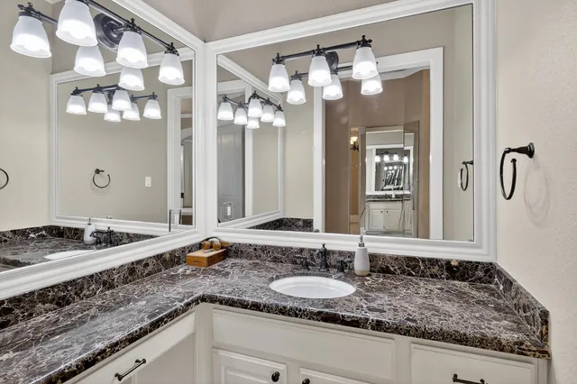 a bathroom with a granite countertop sink and a mirror