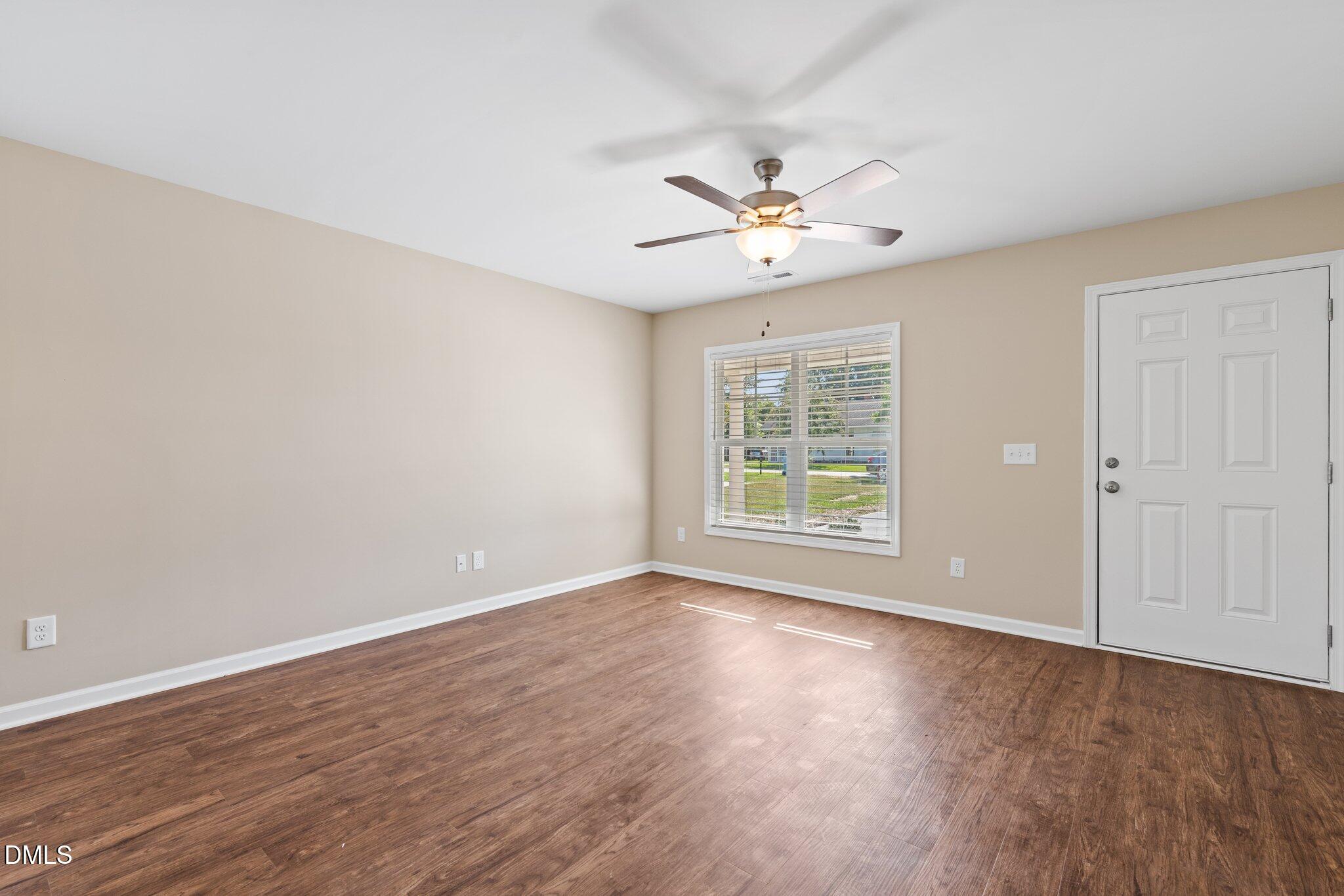 597 Pendergraft Road Bunnlevel, NC 28323 - Photo 6 of 21 an empty room with wooden floor chandelier fan and windows