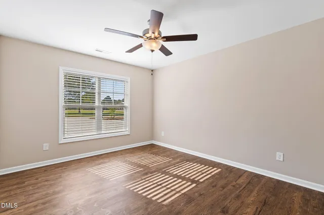 a view of an empty room with wooden floor and a window