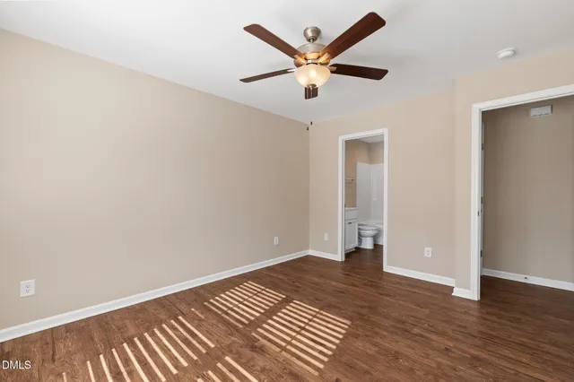 an empty room with wooden floor and a ceiling fan