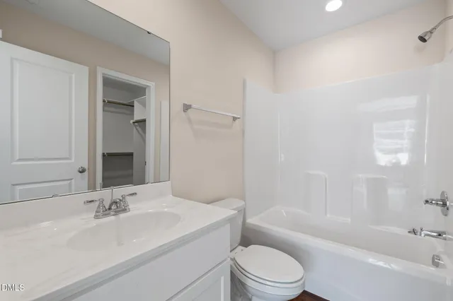 a bathroom with a bathtub shower sink vanity mirror and toilet