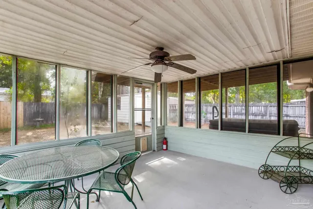 an empty room with chandelier fan and windows