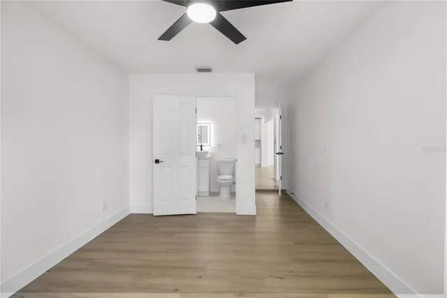 an empty room with wooden floor closet and windows