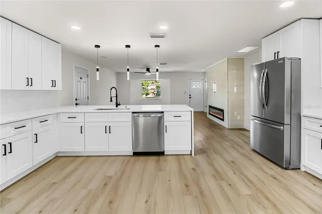 a kitchen with a sink wooden floor and stainless steel appliances