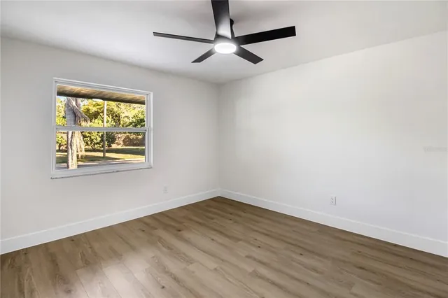 an empty room with wooden floor and ceiling fan