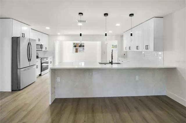 a view of kitchen with wooden floor and electronic appliances