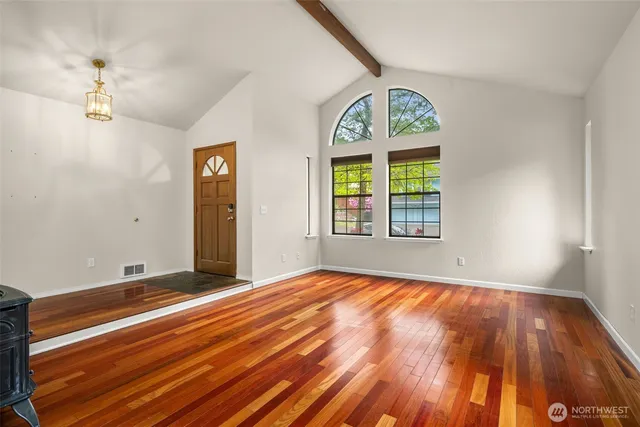 a view of an empty room with window wooden floor and a chandelier
