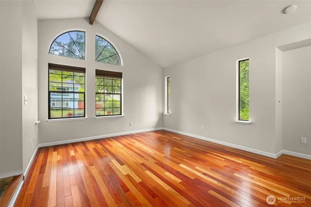 a view of an empty room with a window and wooden floor