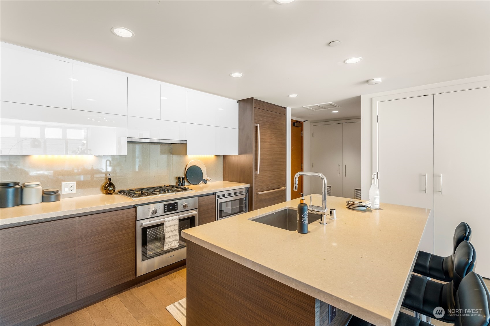 583 Battery Street, Unit 812N Seattle, WA 98121 - Photo 5 of 37 a kitchen with a stove a sink a kitchen island with a dining table and chairs