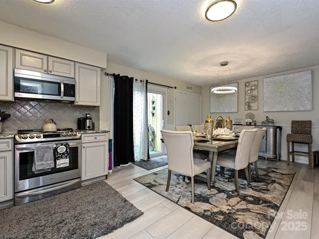 a living room with stainless steel appliances kitchen island granite countertop a stove a sink a microwave and a dining table