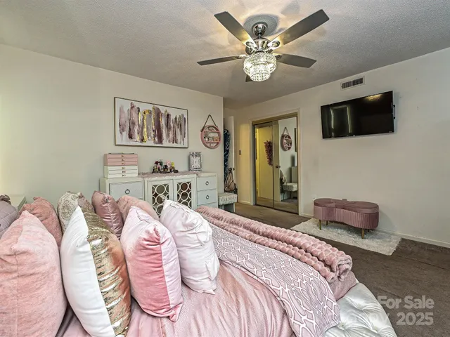 a bedroom with a bed a chandelier and a couch