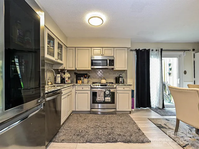a kitchen with stainless steel appliances granite countertop a refrigerator stove top oven and sink