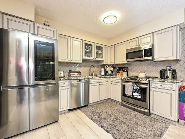 a kitchen with granite countertop stainless steel appliances a stove top oven and a refrigerator