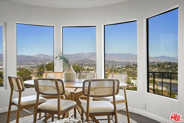 a dining room with furniture large windows and wooden floor