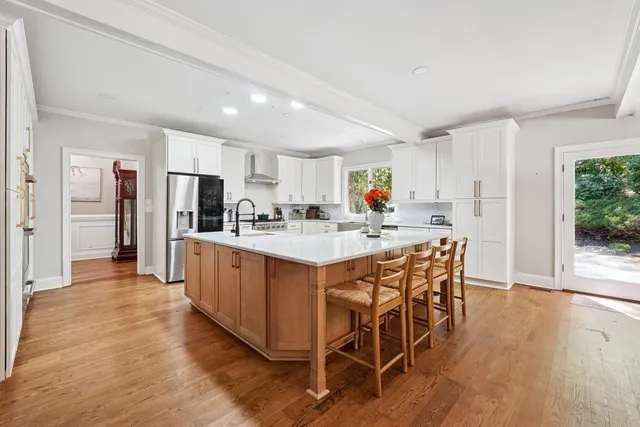 a kitchen with stainless steel appliances kitchen island granite countertop a table chairs refrigerator a sink and dishwasher with wooden floor