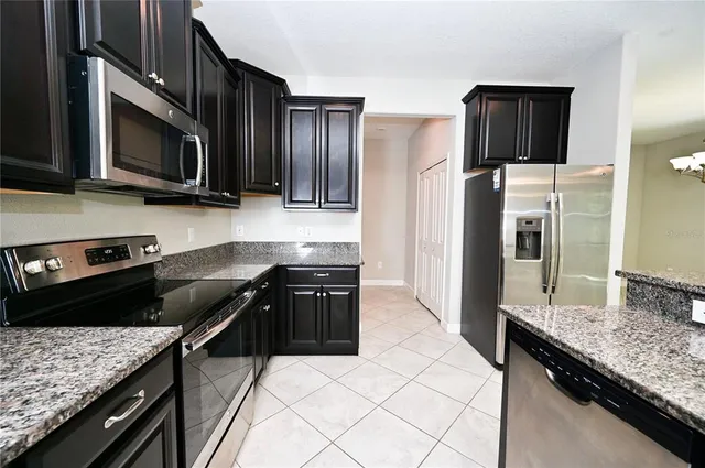 a kitchen with stainless steel appliances granite countertop a stove refrigerator and microwave