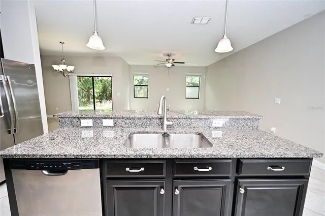 a kitchen with granite countertop a sink a counter space appliances and cabinets